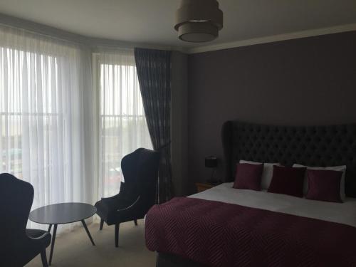 a bedroom with a bed and a table and window at The Clyffe Hotel in Lowestoft