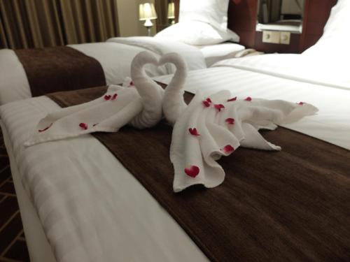 two towels in the shape of swans on a bed at Beijing Xixi Friendship Hotel nearby Xidan Shopping Street, Tian'An Men Square, Forbidden City, Houhai & Jingshan Park in Beijing