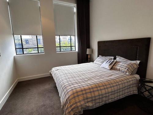een slaapkamer met een bed met 2 kussens en 2 ramen bij THE DEVLIN APARTMENTS 2 Bedroom Apartment near GMHBA stadium in Geelong - G04 in Geelong
