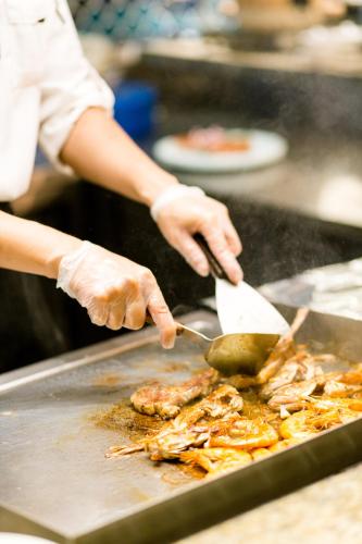 a person is cooking food in a frying pan at Beijing Xixi Friendship Hotel nearby Xidan Shopping Street, Tian'An Men Square, Forbidden City, Houhai & Jingshan Park in Beijing