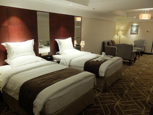 a hotel room with two beds and a chair at Beijing Xixi Friendship Hotel nearby Xidan Shopping Street, Tian'An Men Square, Forbidden City, Houhai & Jingshan Park in Beijing