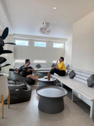 two men sitting on couches in a living room at P168 Hostel Samui in Chaweng