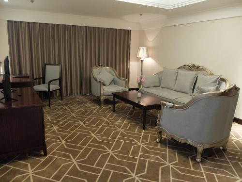 a living room with a couch and a table and chairs at Beijing Xixi Friendship Hotel nearby Xidan Shopping Street, Tian'An Men Square, Forbidden City, Houhai & Jingshan Park in Beijing