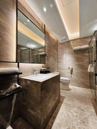 a bathroom with a sink and a toilet and a mirror at Beijing Xixi Friendship Hotel nearby Xidan Shopping Street, Tian'An Men Square, Forbidden City, Houhai & Jingshan Park in Beijing