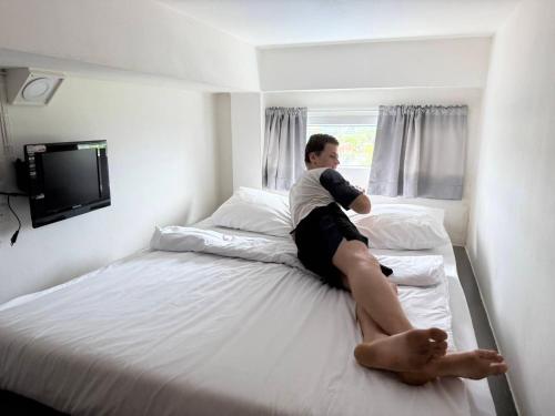 a man sitting on top of a bed at P168 Hostel Samui in Chaweng