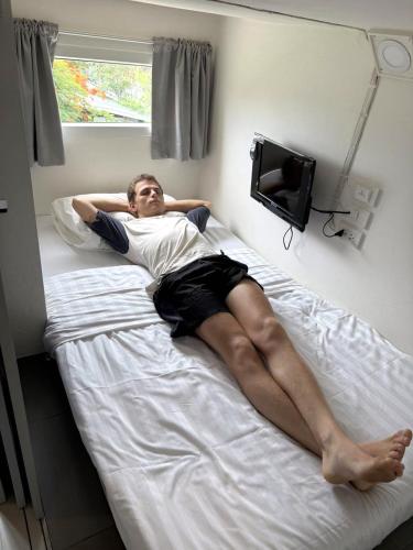 a man laying on a bed in a room at P168 Hostel Samui in Chaweng