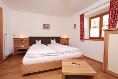 a bedroom with a large white bed and a table at Haus Bergblick in Reit im Winkl