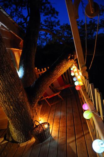 a tree with lights on a deck at night at La Cabane du Vieux Chêne in Susmiou
