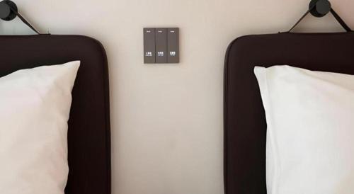 two black beds with pillows and a switch on a wall at Harbour Bay Hotel in Hong Kong