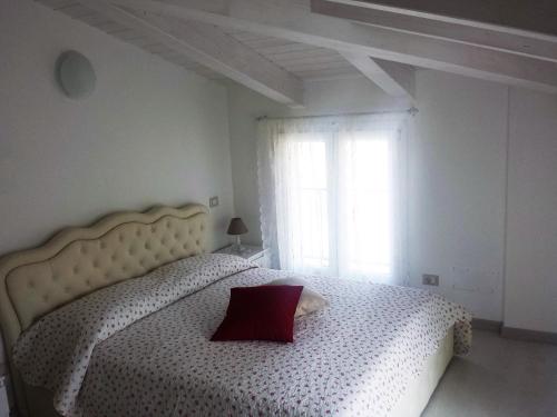 Schlafzimmer mit einem weißen Bett und einem roten Kissen in der Unterkunft Apartments Arcobaleno in Deiva Marina