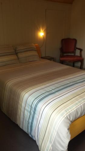 a large bed in a bedroom with a chair at Vakantieverblijf Strandgaper in Oostduinkerke