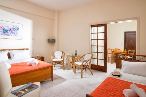 a bedroom with two beds and a table and chairs at Erofili Apartments in Hersonissos