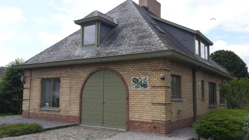 a small brick house with a green garage door at Vakantieverblijf Strandgaper in Oostduinkerke