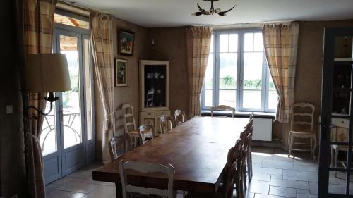 uma sala de jantar com uma grande mesa de madeira e cadeiras em Maison d'hôtes La Tuilerie em Peschadoires