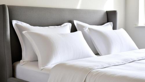 Una cama con sábanas blancas y almohadas. en Cozy haven kitengela, en Kitengela 