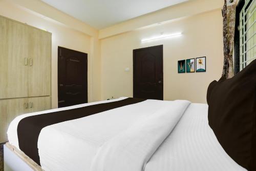 a bedroom with a white bed and two black doors at Collection O Tirupati Railway Junction Formerly Y Stay Home Stay in Tirupati