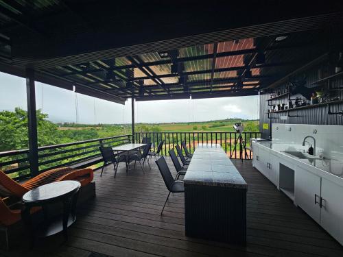 a large deck with a kitchen and tables and chairs at Black Sheep House Khaoyai by ALPHATEL PARTNER in Pong Talong