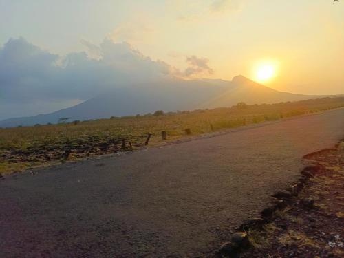 a road with the sun setting on a mountain at Nio Homestay and Tour in Licin