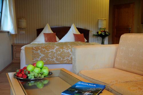 a hotel room with a bed and a bowl of fruit on a table at Hotel Schlossresidenz Heitzenhofen in Duggendorf