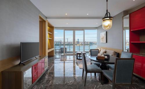 a living room with a tv and a dining table at InterContinental Haikou Seaview by IHG in Haikou