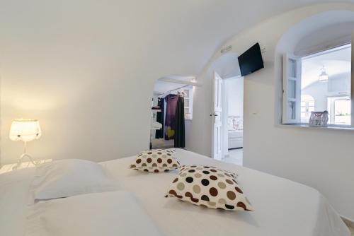 a white bedroom with a bed with pillows on it at Dream Island Hotel in Fira