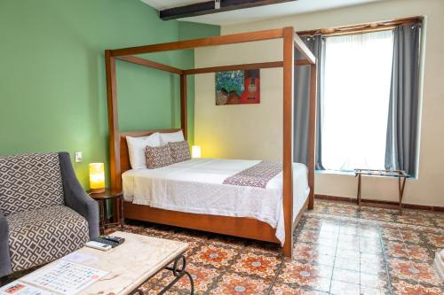 a bedroom with a canopy bed and a couch at Viva Merida Hotel Boutique in Mérida