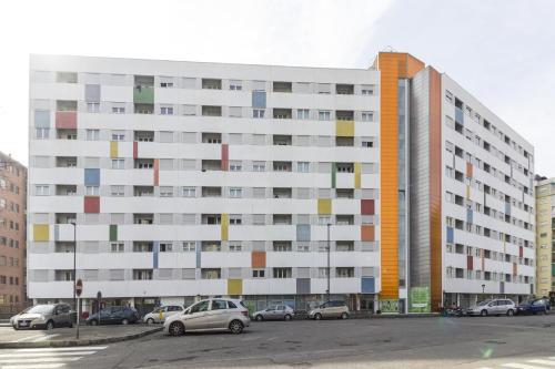 a large white building with cars parked in a parking lot at Hotel Sharing in Turin