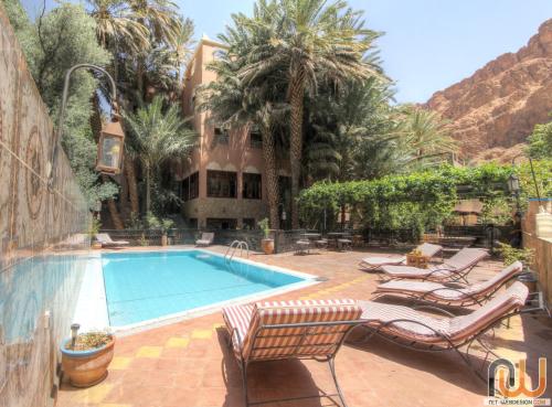 a swimming pool with lounge chairs next to a building at Kasbah Restaurant Amazir in Tinerhir