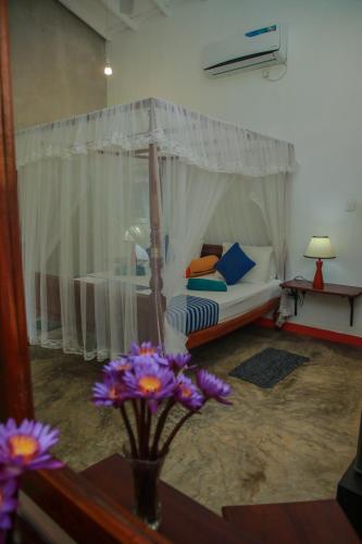 a room with a bed and a table with purple flowers at Villa Gaetano Unawatuna in Unawatuna