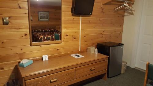 a room with a wooden wall with a dresser and a refrigerator at Clark's Beach Motel in Old Forge
