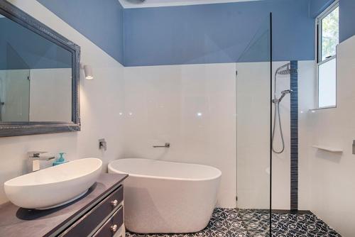 a bathroom with a large white tub and a glass shower at Seashells Beach house on Dorset in Busselton