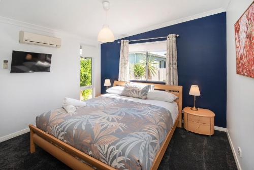a bedroom with a bed with blue walls and a window at Seashells Beach house on Dorset in Busselton