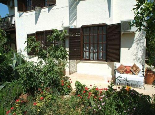 a house with a window and a bench in a garden at Misafir Evi in Kayakoy