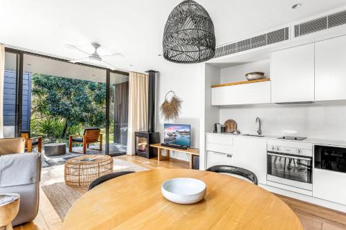 a kitchen and living room with a wooden table at Bangalay Villa 15 just Steps from Seven Mile Beach in Shoalhaven Heads
