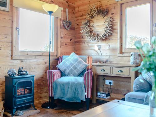 a room with a stove and a chair and a table at Buttercup Lodge in Broomhill