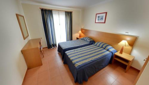 Apartamentos Turísticos Vila Praia tesisinde bir odada yatak veya yataklar