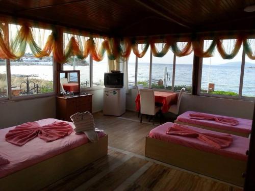 a room with two beds and a desk and a television at Yona Motel in Çeşme
