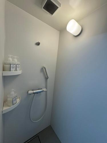a shower in a bathroom with a light on the wall at Thanyaporn Hotel in Takayama