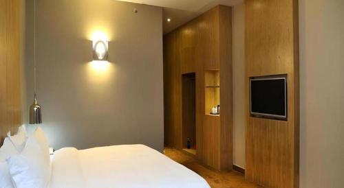 a bedroom with a white bed and a flat screen tv at The Art Hotel in Shenzhen