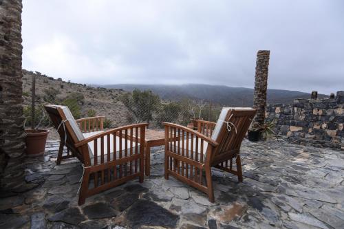 three chairs sitting on a stone patio with a view at Sama Heights Resort in Dār Sawdāʼ