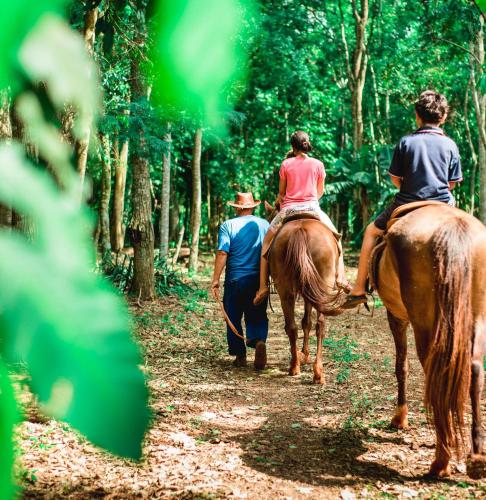 a group of people riding horses down a dirt trail at Canzi Cataratas Hotel in Foz do Iguaçu