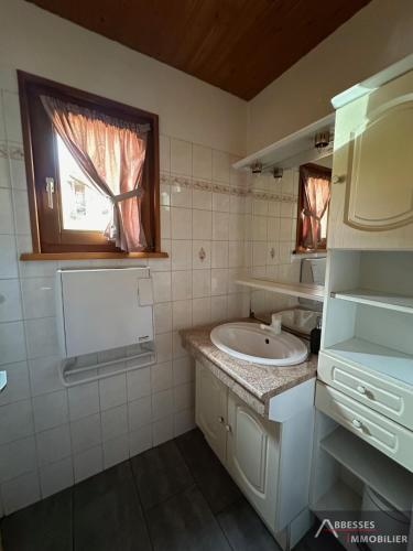 a white bathroom with a sink and a window at Chalet Les Jonquilles in Gérardmer