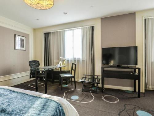 a hotel room with a bed and a television and a table at Jinjiang Metropolo Hotel Classiq YMCA People Square in Shanghai