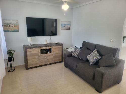a living room with a couch and a flat screen tv at Casa Lily in Mazarrón