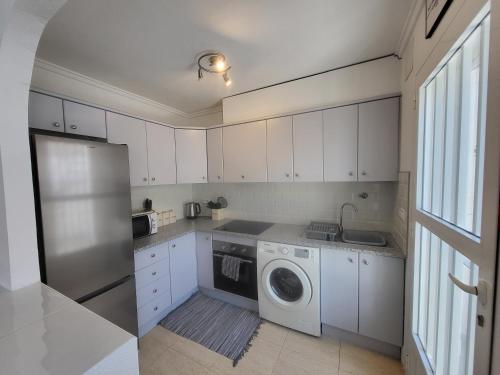 a kitchen with white cabinets and a washing machine at Casa Lily in Mazarrón