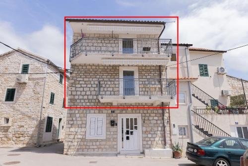 a large stone building with a red box at Apartments Kastilac near the beach in Kaštela
