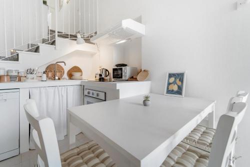 a white kitchen with a white table and chairs at Domu Istella in SantʼAnna Arresi