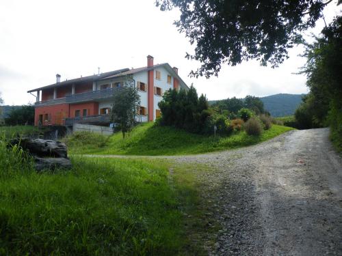 une maison sur une colline à côté d'une route en gravier dans l'établissement Agriturismo Al Bachero, à Belluno