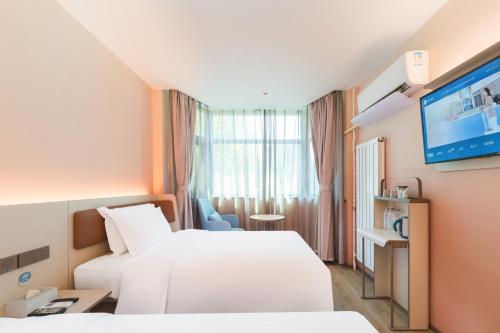 a hotel room with two beds and a flat screen tv at Hanting Hotel Beijing Jiaotong University Zoo in Beijing