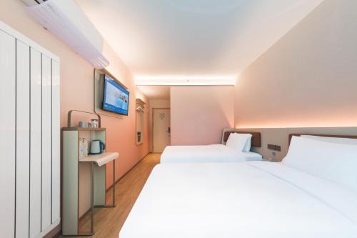 a hotel room with two beds and a tv at Hanting Hotel Beijing Jiaotong University Zoo in Beijing
